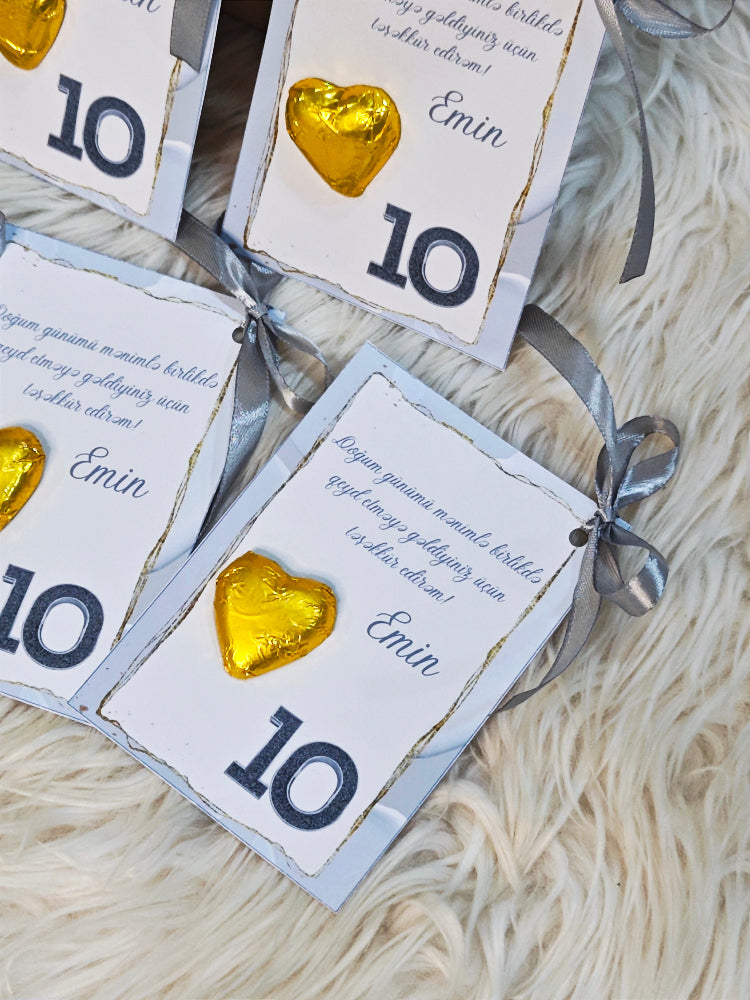 Gift cards with gold heart-shaped chocolates and ribbons on a textured surface