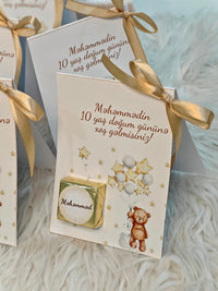Greeting card with teddy bear illustration and gold ribbon on a soft surface