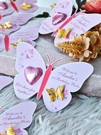 Butterfly-shaped party invitations with decorative elements on a textured surface.