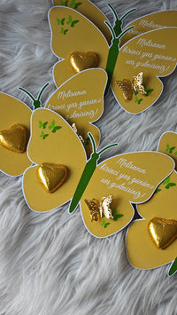 Yellow butterfly-shaped cards with gold hearts on a fluffy white surface