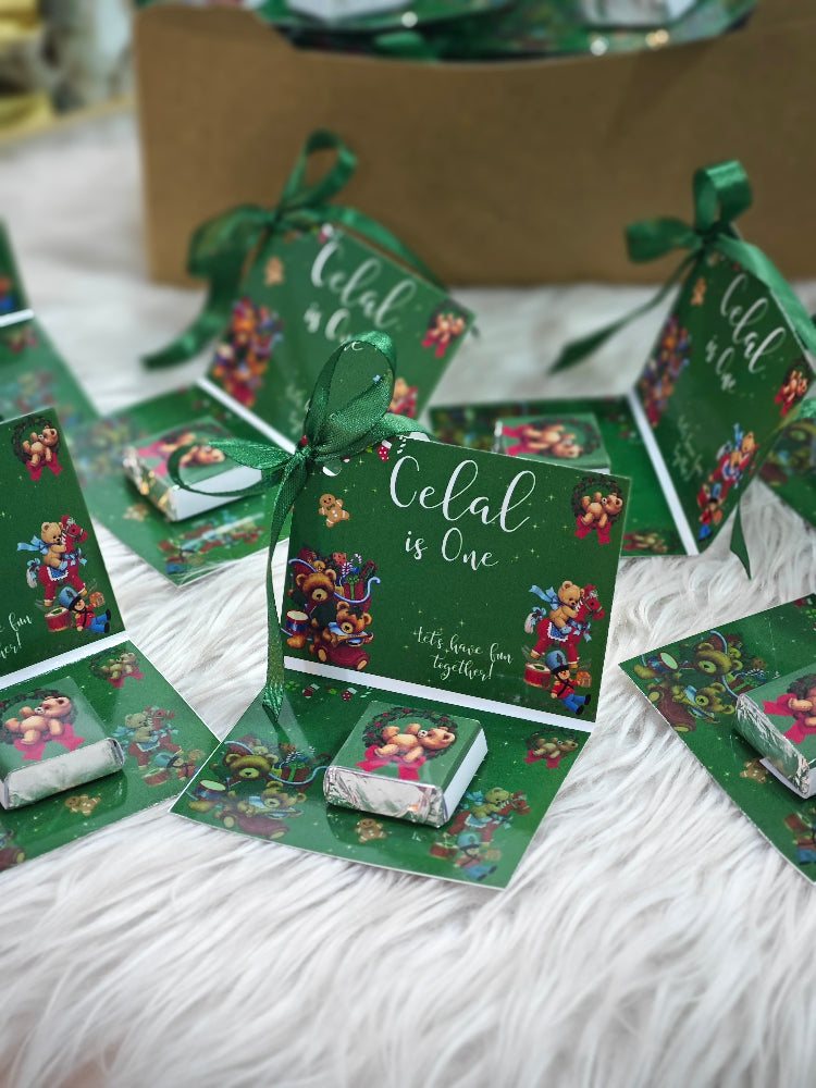 Green party favor bags with colorful designs and ribbons on a white surface.
