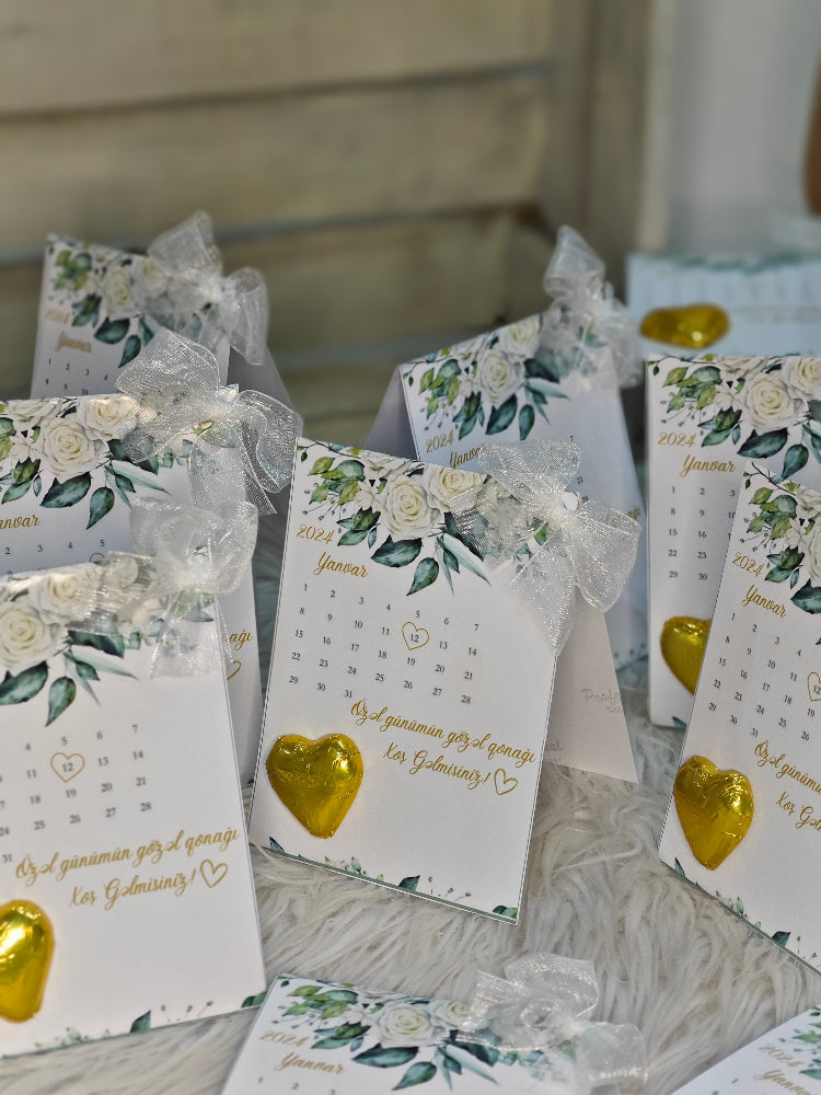 Small gift bags with floral designs and gold hearts on a wooden surface.