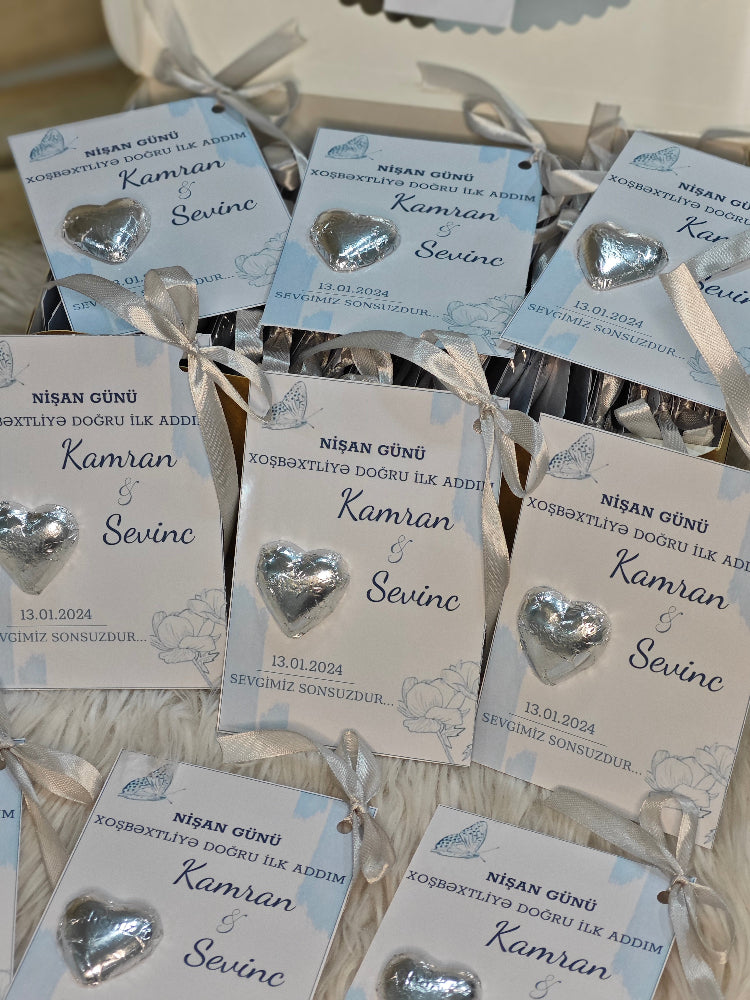 Heart-shaped silver earrings on cards with personalized text in a box.