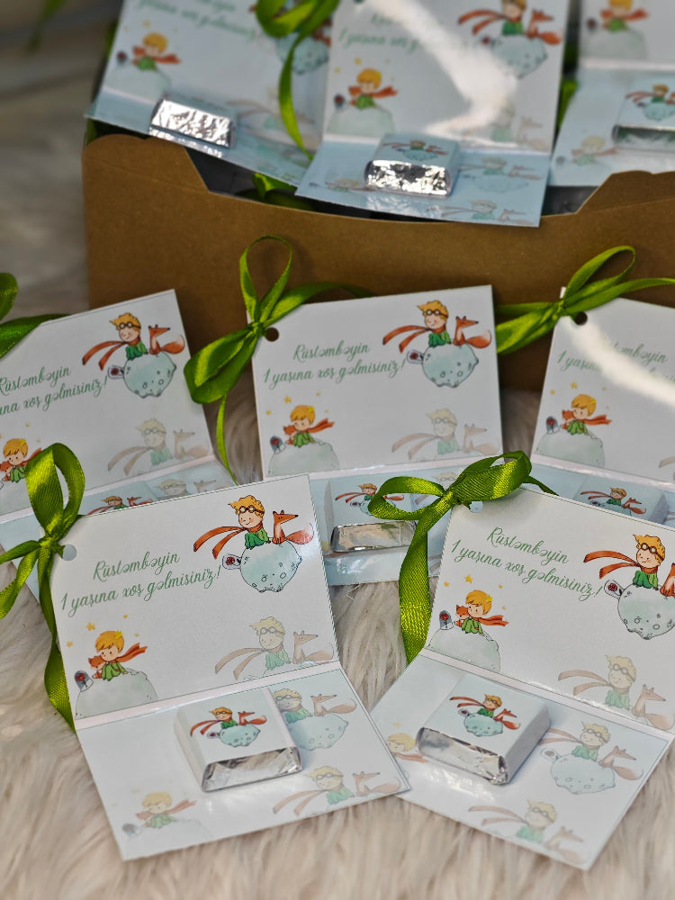 Small boxes with illustrations and green ribbons on a wooden surface