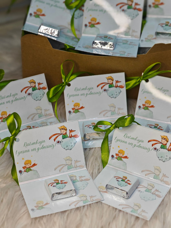 Small boxes with illustrations and green ribbons on a wooden surface