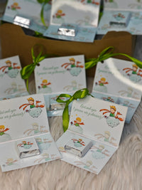 Small boxes with illustrations and green ribbons on a wooden surface