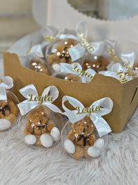 Teddy bears in clear plastic bags with white ribbons and 'Leyla' branding, inside a cardboard box.
