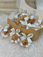 Decorative bear ornaments with white bows and 'Leyla' text in a wooden box on a textured surface.