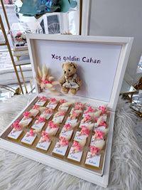 Decorative box with teddy bear, flowers, and personalized text on a light background