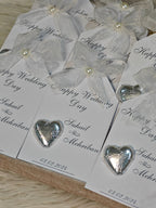 Silver heart-shaped candies on wedding favor bags with 'Happy Wedding Day' text.