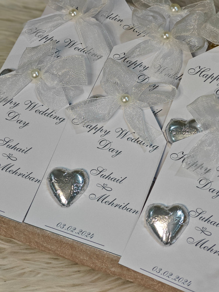Silver heart-shaped candies on wedding favor bags with 'Happy Wedding Day' text.