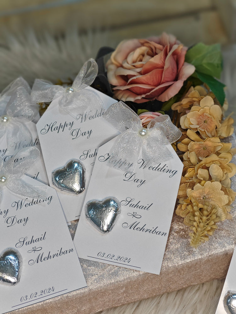 Heart-shaped earrings on 'Happy Wedding Day' tags with flowers in the background