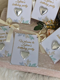 Invitations for Zahra's birthday party with heart-shaped decorations on a textured surface.
