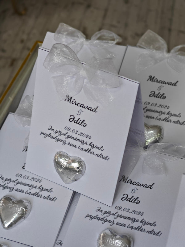Silver heart-shaped earrings in packaging with personalized text on a wooden surface.