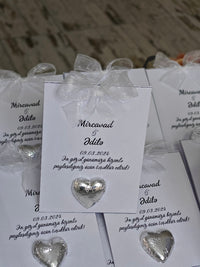 Silver heart-shaped earrings on branded cards with text.