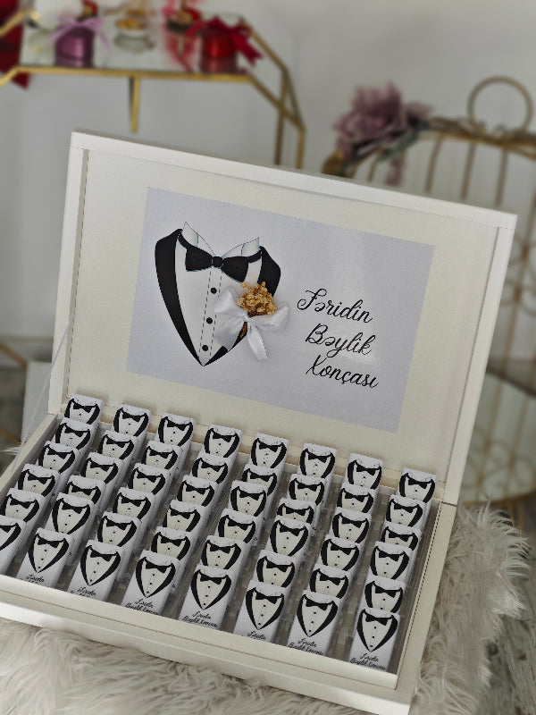 Wooden box with tuxedo designs and a card inside, on a soft surface.