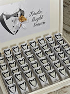 Box of chocolate bars with tuxedo design and a decorative card on a wooden surface.