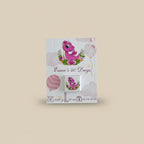Pink dinosaur-themed baby shower favor boxes with ribbons on a wooden surface.