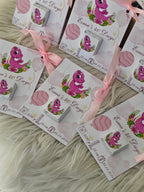 Set of baby shower favor boxes with pink dinosaur design on a fluffy white surface