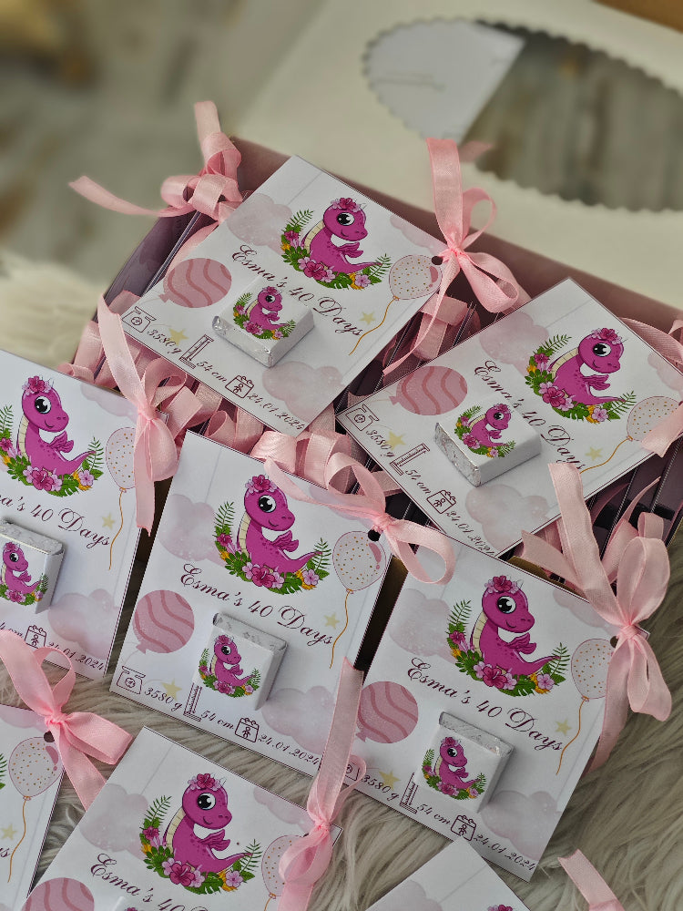 Packaged items with pink ribbons and dinosaur illustrations on a wooden surface.