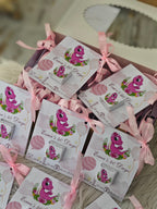 Packaged items with pink ribbons and dinosaur illustrations on a wooden surface.
