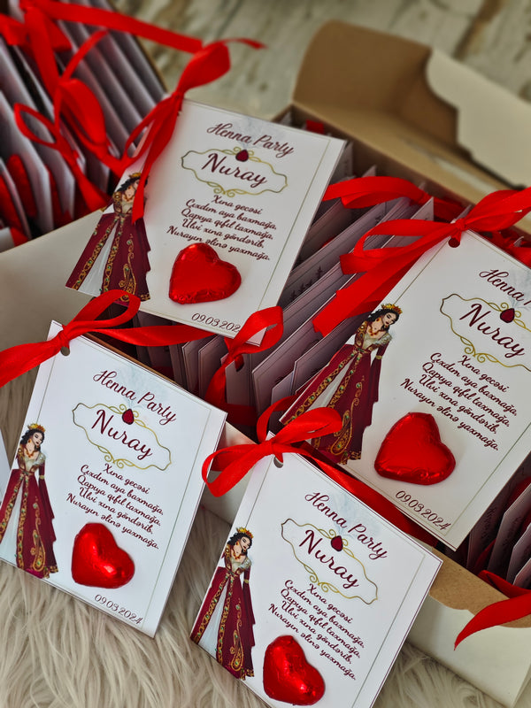 Small boxes with red ribbons and decorative cards on a textured surface
