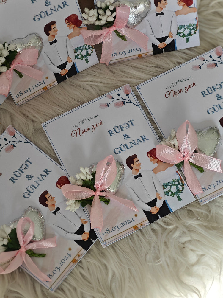 Wedding invitations with cartoon couple and pink ribbons on a textured surface