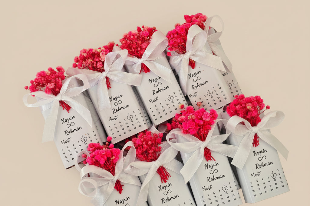 Small bottles with red flowers and white ribbons in a box