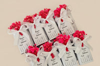 Small bottles with red flowers and white ribbons in a box