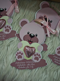Card with a teddy bear design holding a heart on a textured green surface