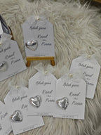 Heart-shaped silver earrings on branded cards with a white fluffy background
