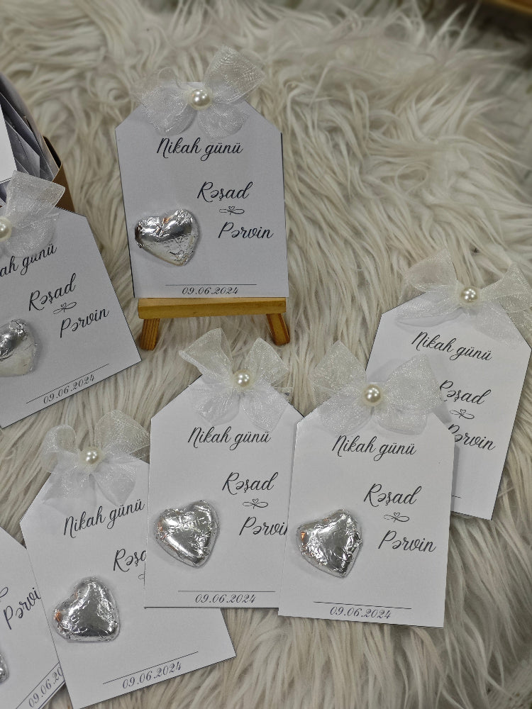 Heart-shaped silver earrings on branded cards with a white fluffy background