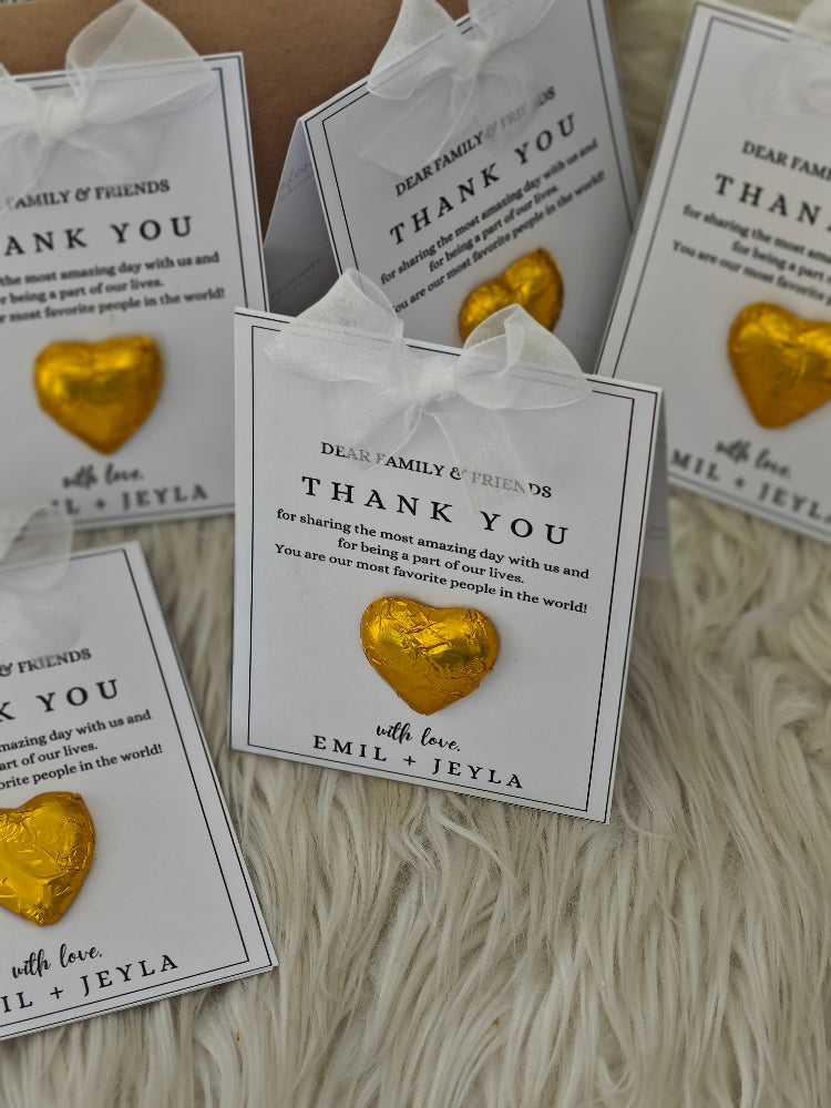 Gold heart-shaped favors on thank you cards with a white background