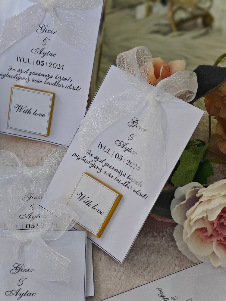 Wedding invitation cards with decorative ribbons and flowers on a table.