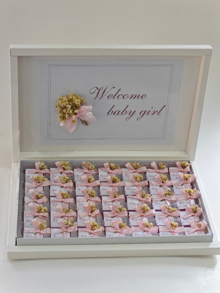 Decorative box with 'Welcome baby girl' text and small packages inside.
