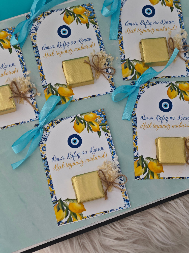 Packaged gold bars with decorative labels and ribbons on a light blue surface