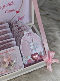 Decorative card with a rabbit illustration and pink ribbon on a textured surface