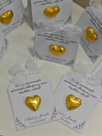 Gold heart-shaped earrings on white cards with text, displayed on a white surface.