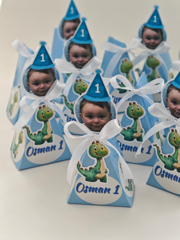 Children's party favor boxes with blue hats and dinosaur graphics on a white background