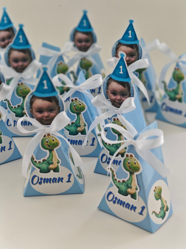 Small blue gift bags with dinosaur stickers and white ribbons, personalized with names and numbers.