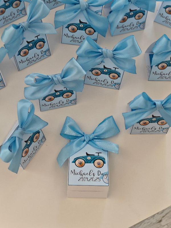 Small boxes with blue ribbons and 'Michael's Day 2023' text on a white surface
