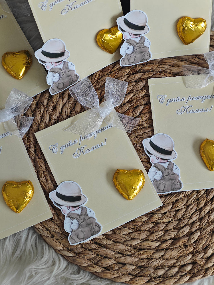 Cards with teddy bear stickers and gold heart-shaped candies on a woven mat.