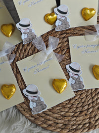 Cards with teddy bear stickers and gold heart-shaped candies on a woven mat.