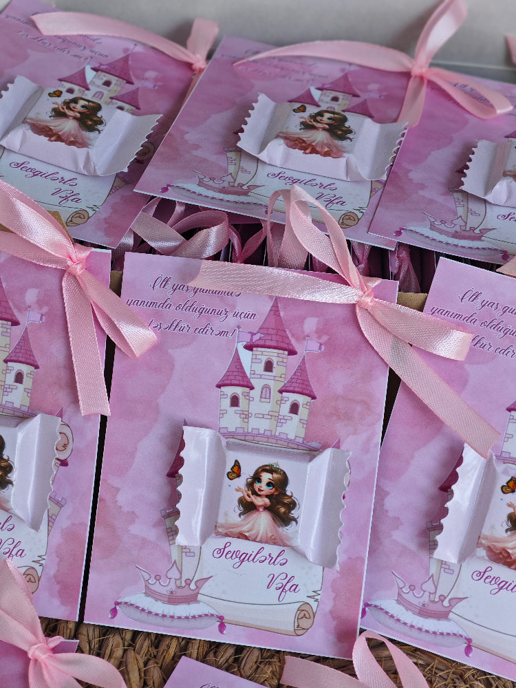 Pink party favor bags with princess design and ribbons on a wooden surface.