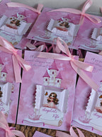 Pink party favor bags with princess design and ribbons on a wooden surface.