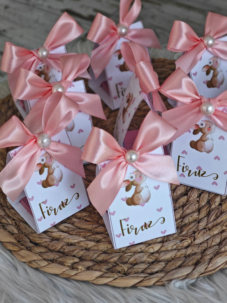 Small boxes with pink ribbons and 'Firne' labels on a woven mat.