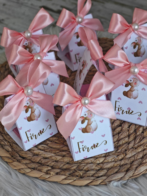 Small boxes with pink ribbons and 'Firne' labels on a woven mat.