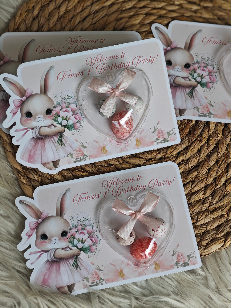 Decorative birthday party invitations with rabbit illustrations on a woven surface.