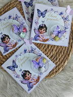 Set of greeting cards with fairy illustrations and purple butterflies on a woven surface.