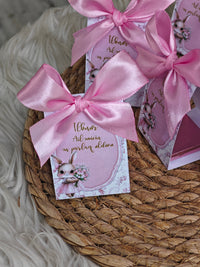 Pink gift cards with ribbons on a woven surface